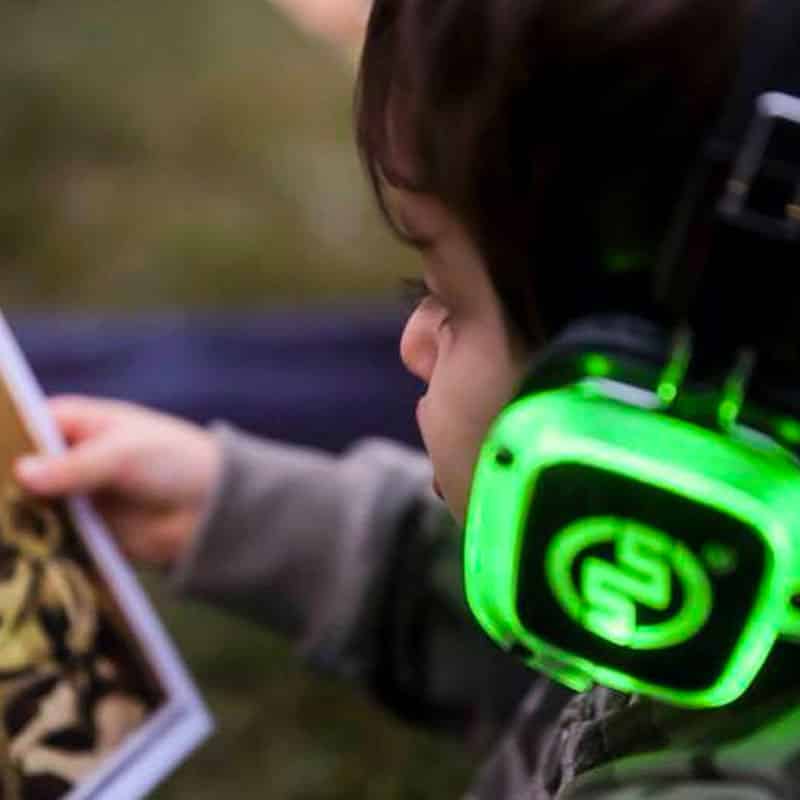 silentparty-bambini Kind mit grünen Silent-Disco-Kopfhörern betrachtet eine Postkarte