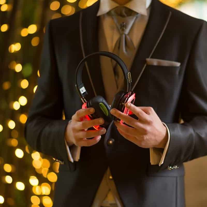 matrimonio Bräutigam im eleganten Anzug hält Silent-Disco-Kopfhörer in der Hand