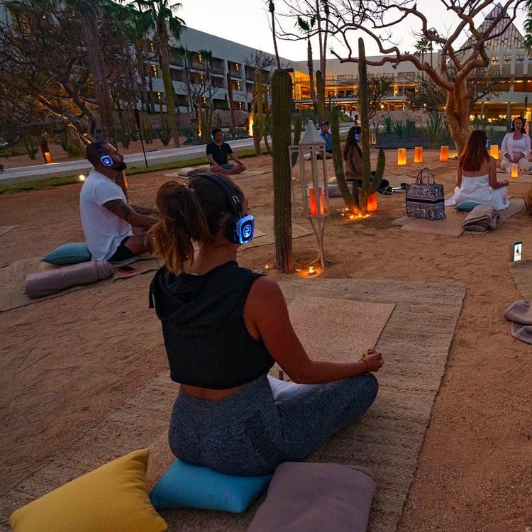 yogasensoriale Sensorisches Yoga bei Sonnenuntergang mit kabellosen Kopfhörern und Kerzen