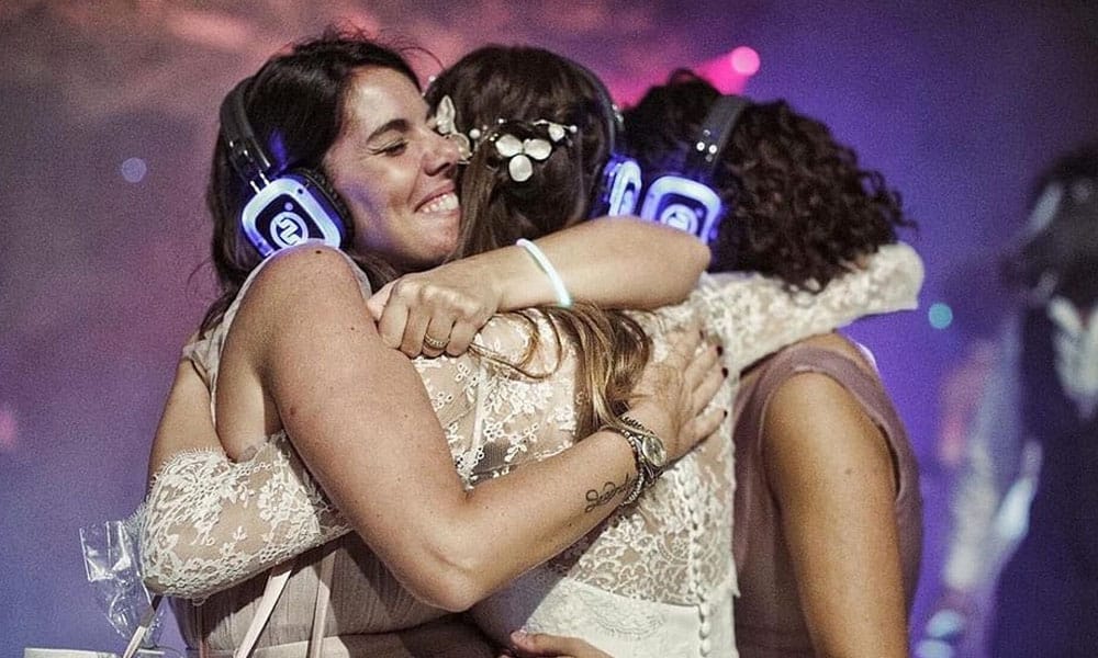 Matrimonio silentdisco Braut umarmt ihre Freundinnen mit Silent-Disco-Kopfhörern